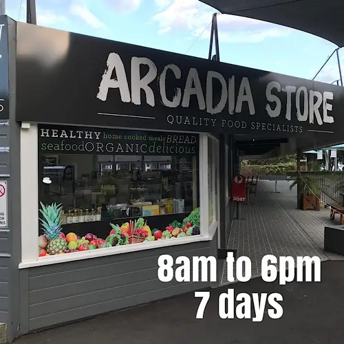 Exterior of Arcadia Store with large windows displaying fresh fruit and signage reading “Healthy home‑cooked meals, bread, seafood, organic, delicious.” Store hours shown as “8am to 6pm, 7 days.”
